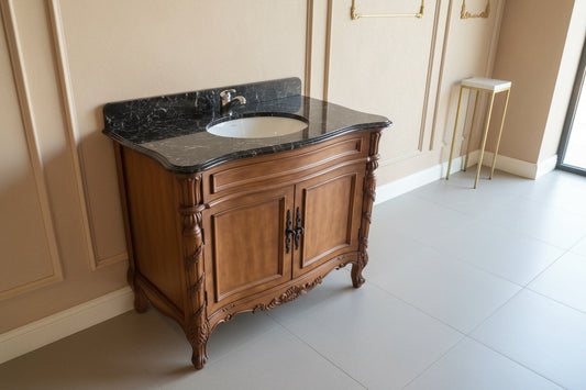 Wooden vanity with black countertop and white sink in a room setting.