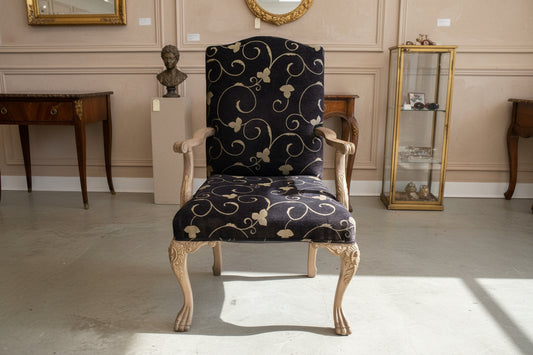 Pair of patterned pants hanging on a wooden hanger against a textured wall.